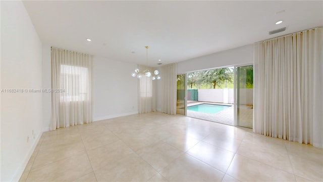 spare room with a chandelier and light tile patterned flooring