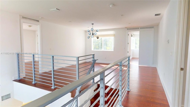 corridor with an inviting chandelier and hardwood / wood-style flooring