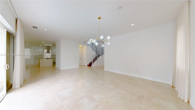 tiled spare room featuring a notable chandelier