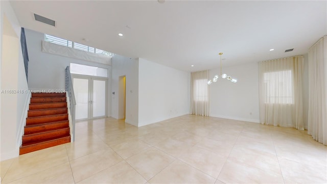 tiled spare room with a chandelier and french doors