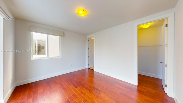 unfurnished bedroom with a walk in closet, wood-type flooring, and a closet