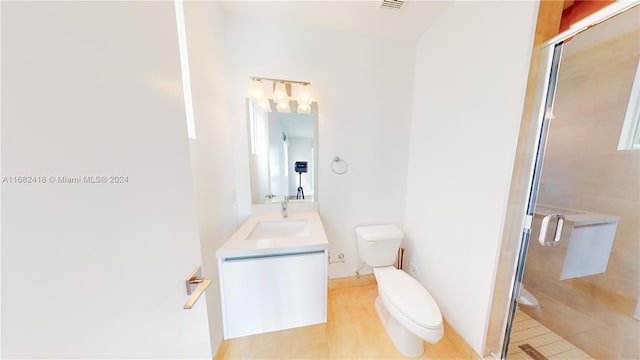 bathroom featuring toilet, a shower with shower door, vanity, and tile patterned floors