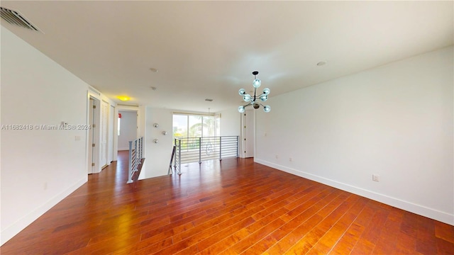 unfurnished room with hardwood / wood-style flooring and an inviting chandelier