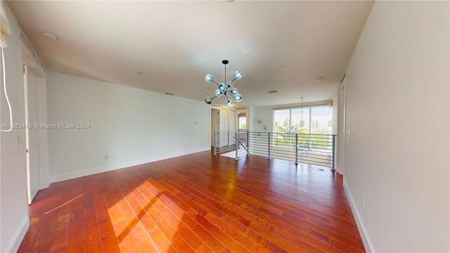 empty room with a notable chandelier and hardwood / wood-style flooring