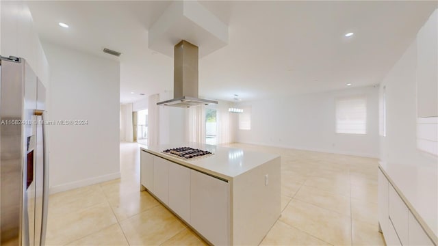 kitchen featuring island exhaust hood, light tile patterned flooring, a center island, white cabinets, and appliances with stainless steel finishes