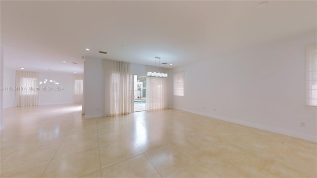 tiled empty room featuring an inviting chandelier