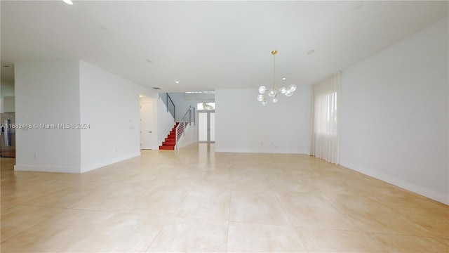 spare room featuring light tile patterned flooring and a chandelier