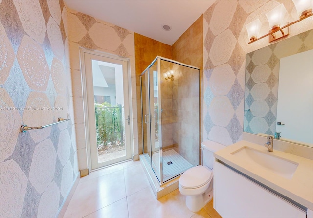 bathroom with tile patterned floors, toilet, vanity, tile walls, and walk in shower