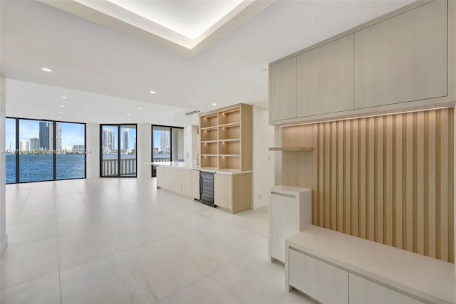 unfurnished living room with a water view, wine cooler, and floor to ceiling windows