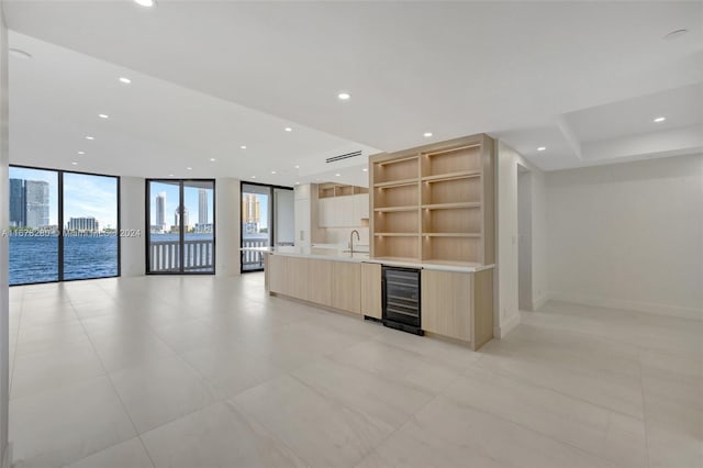 kitchen featuring wine cooler, sink, light brown cabinetry, a water view, and floor to ceiling windows