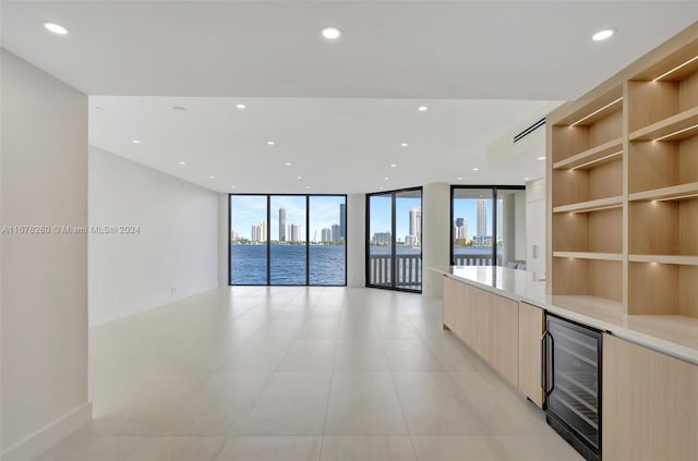 unfurnished room with a wall of windows, light tile patterned floors, a city view, wine cooler, and recessed lighting