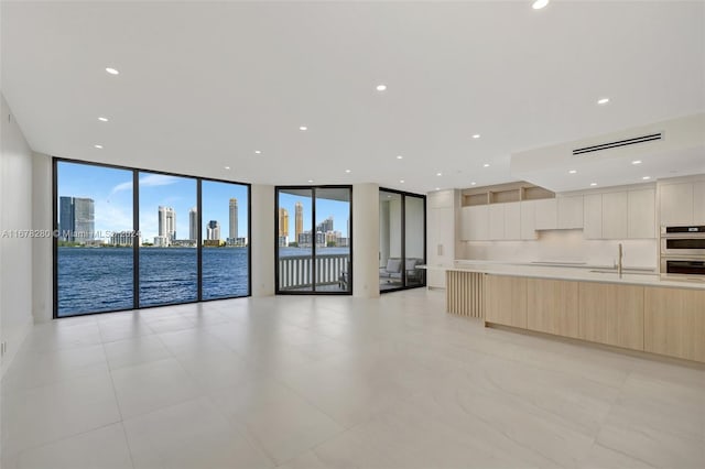 interior space featuring a water view, sink, plenty of natural light, and a wall of windows