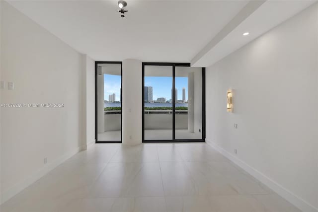 spare room featuring expansive windows and light tile patterned flooring