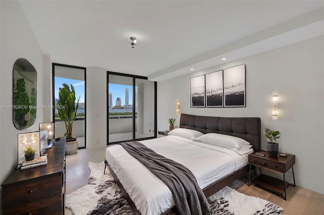 bedroom with a wall of windows and light wood-type flooring