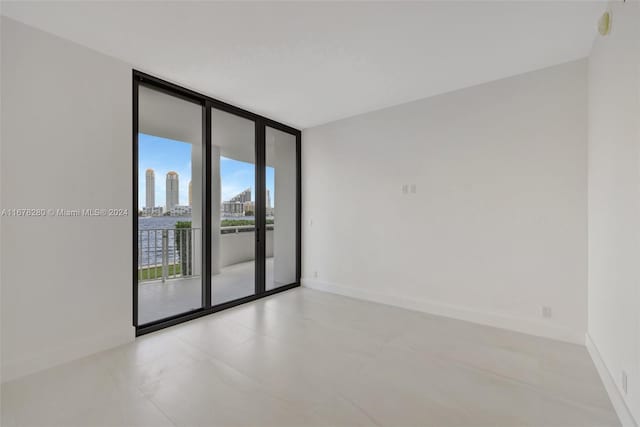 unfurnished room featuring a wall of windows and baseboards