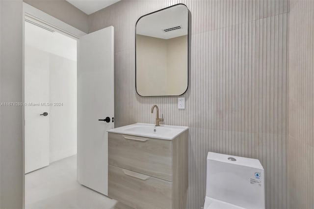 bathroom with vanity, toilet, and tile walls