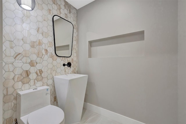 bathroom with toilet, baseboards, and tile walls
