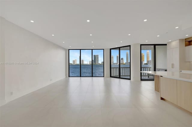 spare room featuring a water view and a wall of windows