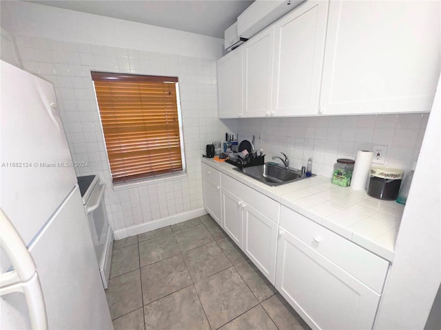 kitchen featuring light tile patterned floors, white cabinetry, tile counters, sink, and white appliances