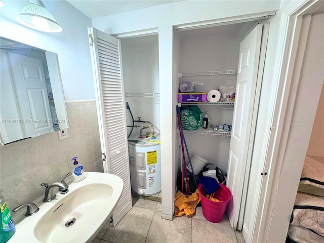 bathroom featuring electric water heater, sink, tile walls, and tile patterned flooring