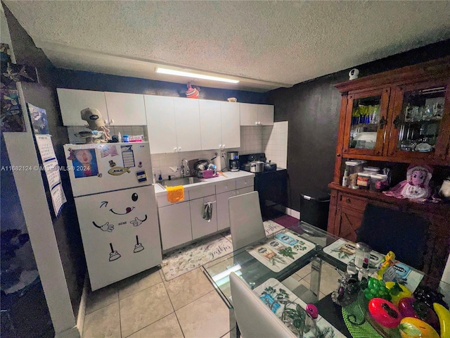 kitchen with white cabinets, tasteful backsplash, a textured ceiling, and white refrigerator