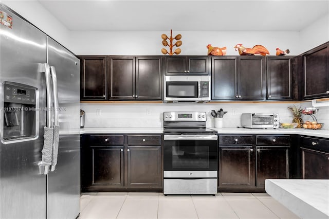 kitchen with appliances with stainless steel finishes, light tile patterned floors, and dark brown cabinets