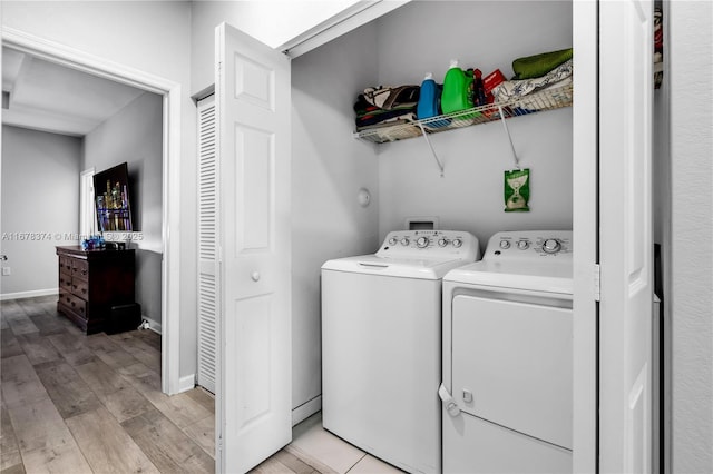 laundry room with washing machine and clothes dryer and light wood-type flooring