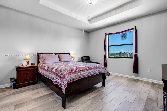 bedroom featuring a tray ceiling and light hardwood / wood-style flooring