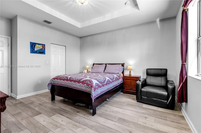 bedroom with a tray ceiling and light hardwood / wood-style floors