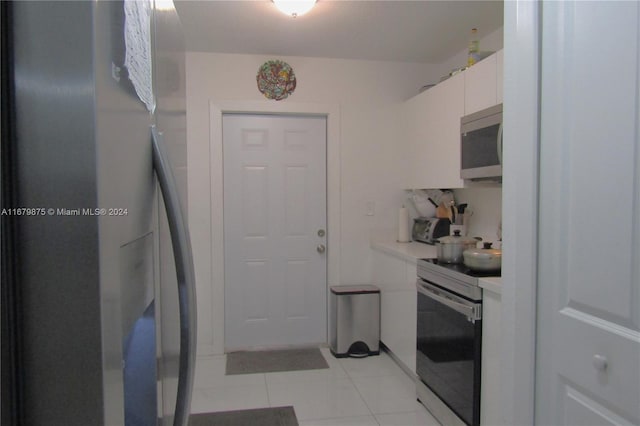 kitchen with white cabinetry, stainless steel appliances, and light tile patterned flooring