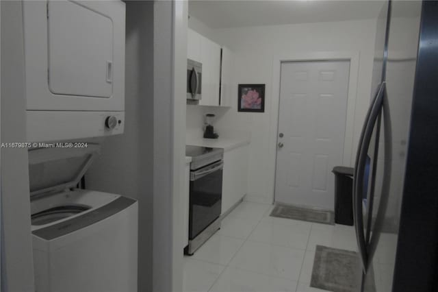 laundry area with stacked washer / dryer and light tile patterned flooring