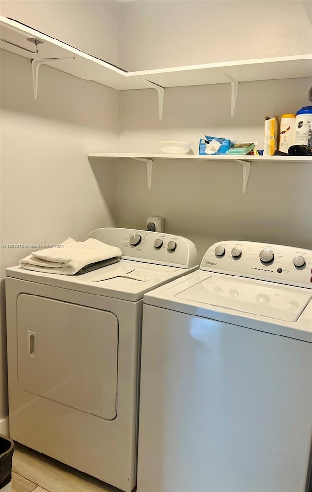 laundry area featuring washing machine and dryer and light hardwood / wood-style flooring
