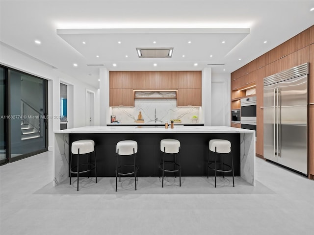 kitchen featuring sink, tasteful backsplash, a large island, a kitchen bar, and stainless steel appliances