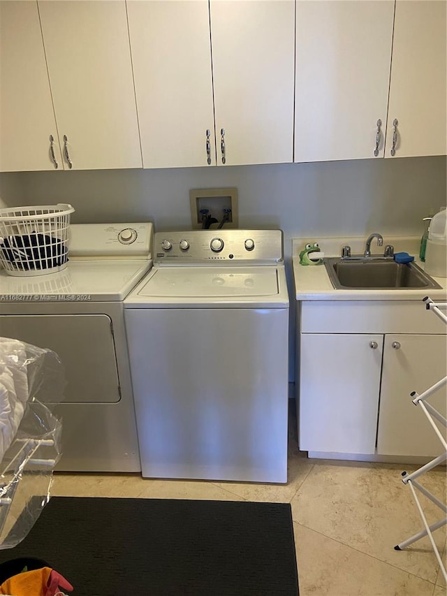 clothes washing area featuring cabinets, light tile patterned flooring, sink, and washing machine and dryer