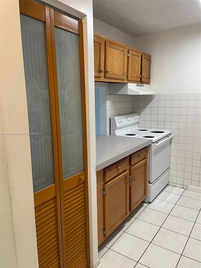 kitchen with tile walls, white range with electric cooktop, a textured ceiling, and light tile patterned floors