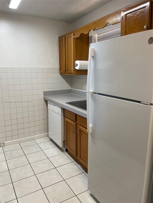 kitchen with tile walls, sink, white appliances, and light tile patterned floors