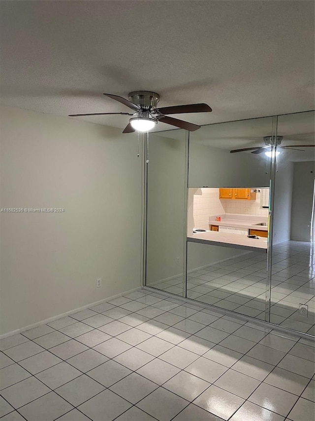 empty room with a textured ceiling, light tile patterned floors, and ceiling fan