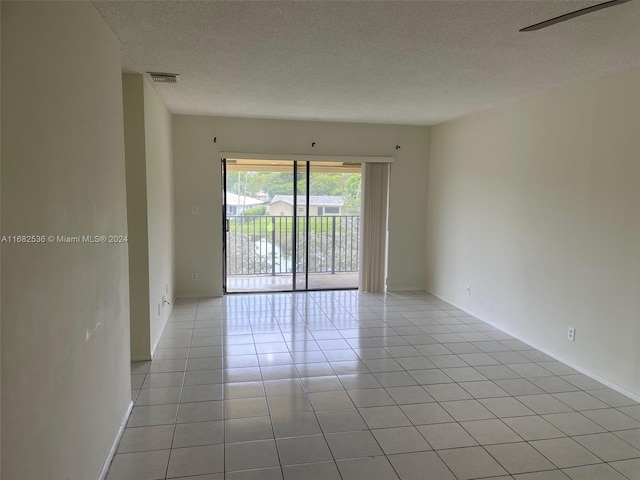 tiled empty room featuring a textured ceiling