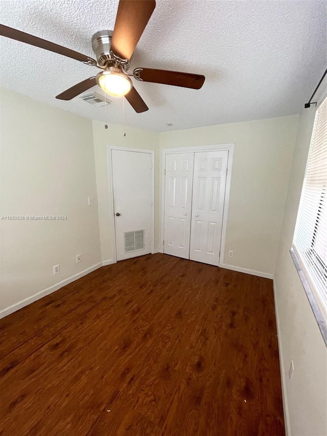 unfurnished bedroom with dark hardwood / wood-style floors, a textured ceiling, and ceiling fan