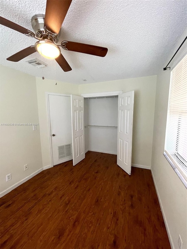 unfurnished bedroom with ceiling fan, a textured ceiling, and dark hardwood / wood-style flooring