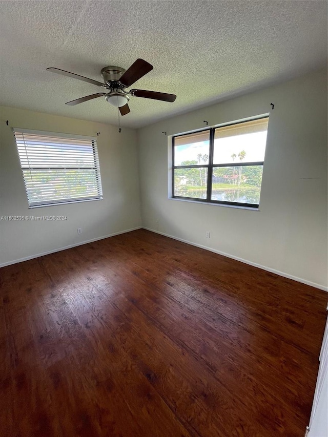 empty room featuring a textured ceiling, dark wood-type flooring, and ceiling fan