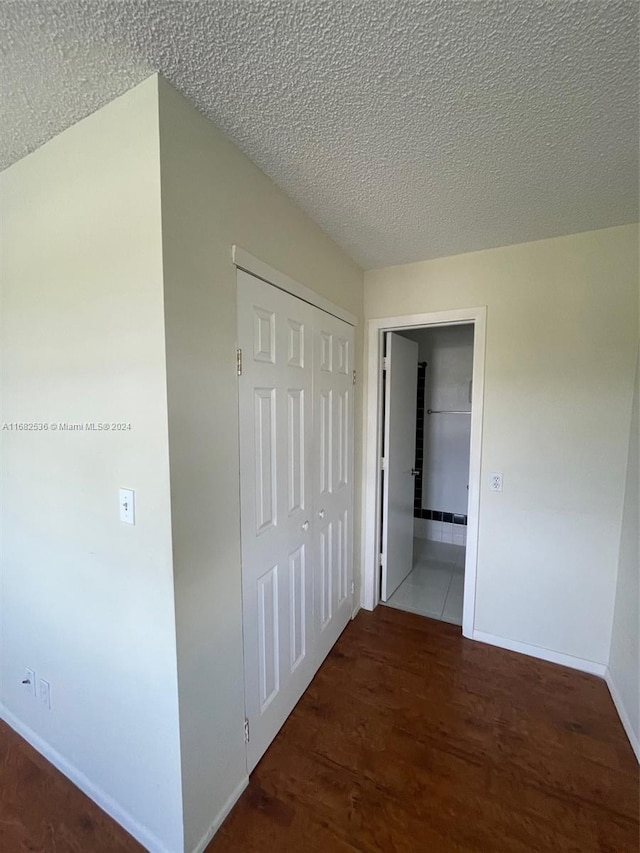 corridor featuring dark wood-type flooring and a textured ceiling