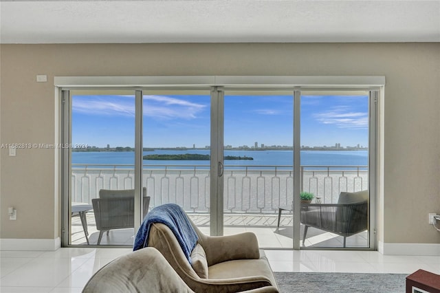 living room with a water view, a beach view, and tile patterned flooring