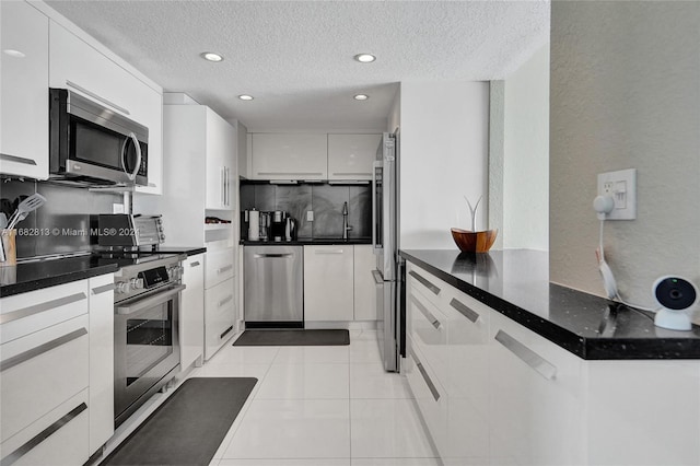 kitchen featuring appliances with stainless steel finishes, white cabinetry, a textured ceiling, and light tile patterned floors