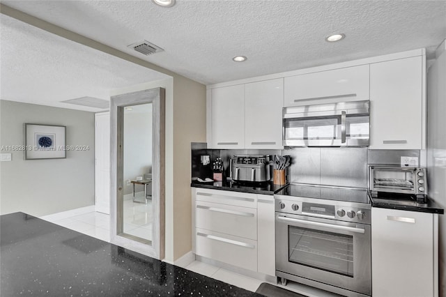 kitchen featuring a textured ceiling, white cabinetry, stainless steel appliances, and light tile patterned floors