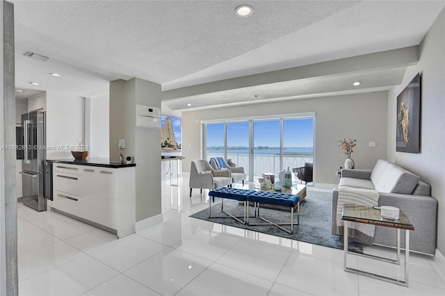 tiled living room with a textured ceiling and a water view