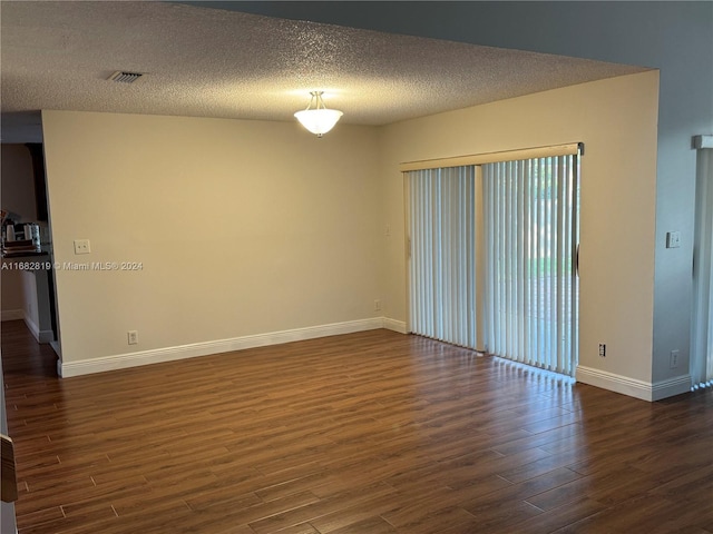 empty room featuring a textured ceiling and dark hardwood / wood-style flooring