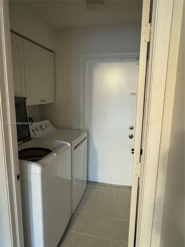 clothes washing area featuring light tile patterned flooring, cabinets, and separate washer and dryer