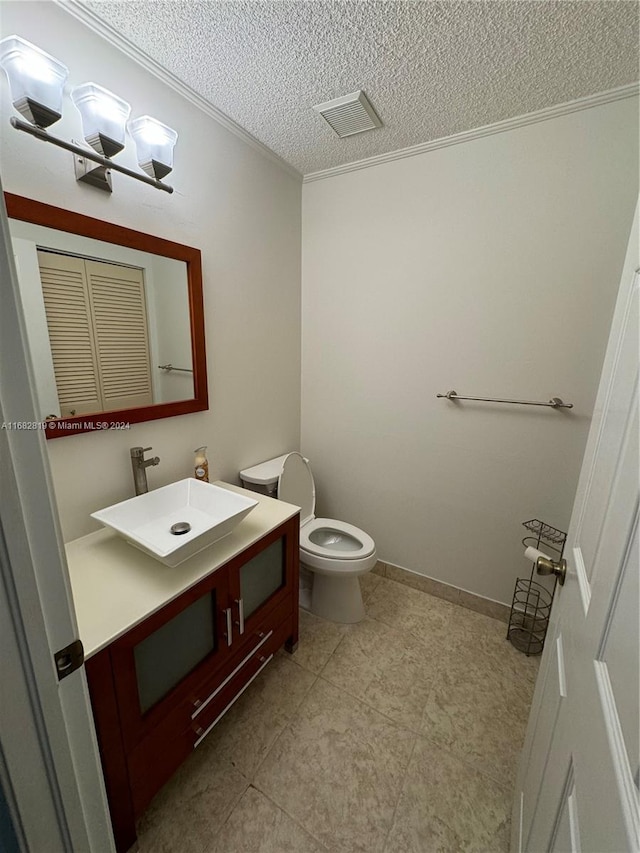 bathroom featuring vanity, a textured ceiling, toilet, and ornamental molding