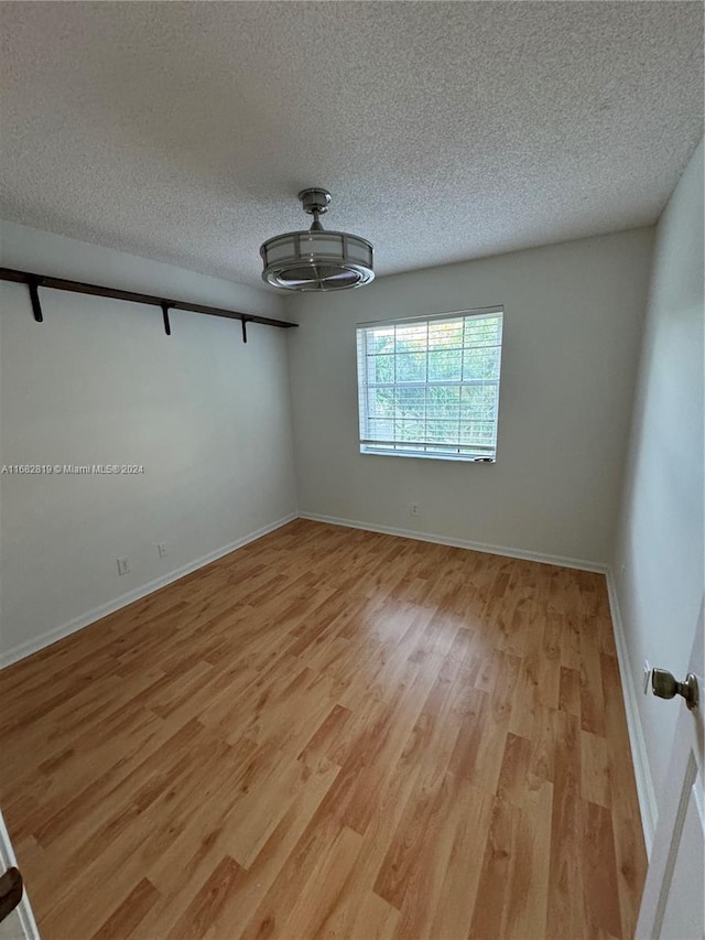 unfurnished room featuring a textured ceiling and light hardwood / wood-style flooring